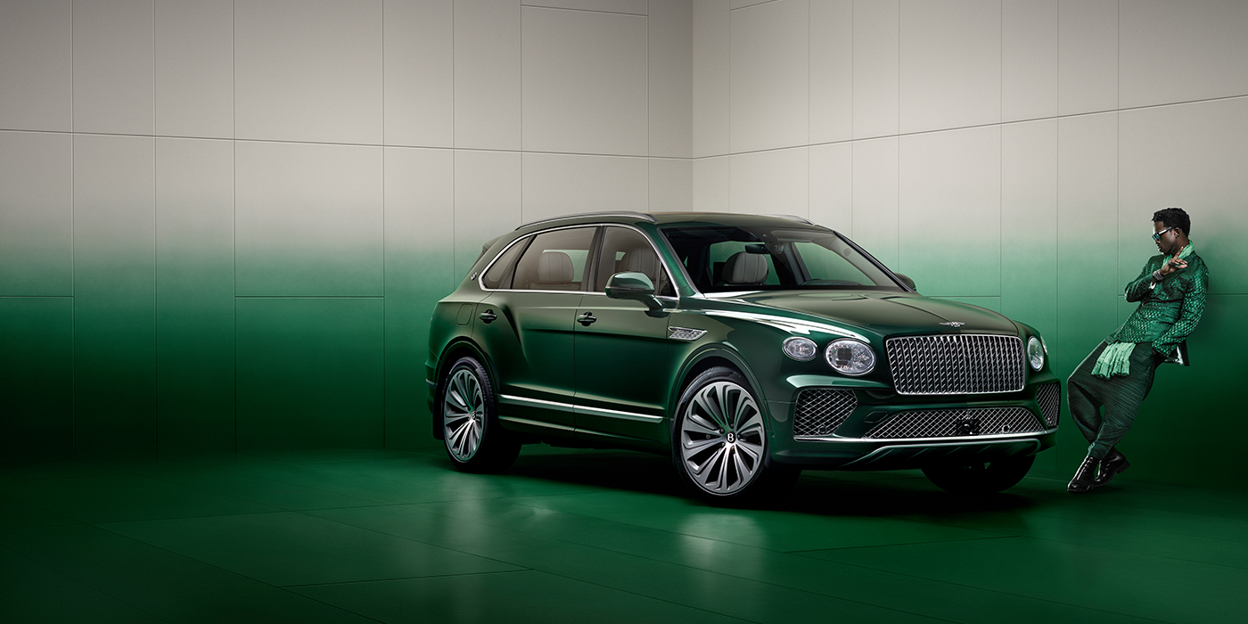 Bentley Kuala Lumpur Wisdom K leans against wall next to Bentley Bentayga Extended Wheelbase Atelier Edition SUV in Light Emerald green paint