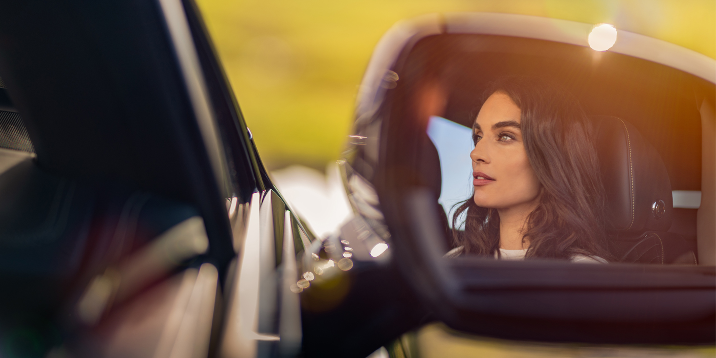 Bentley Kuala Lumpur profile of dark haired woman's face in mirror of Bentley car in sunlight