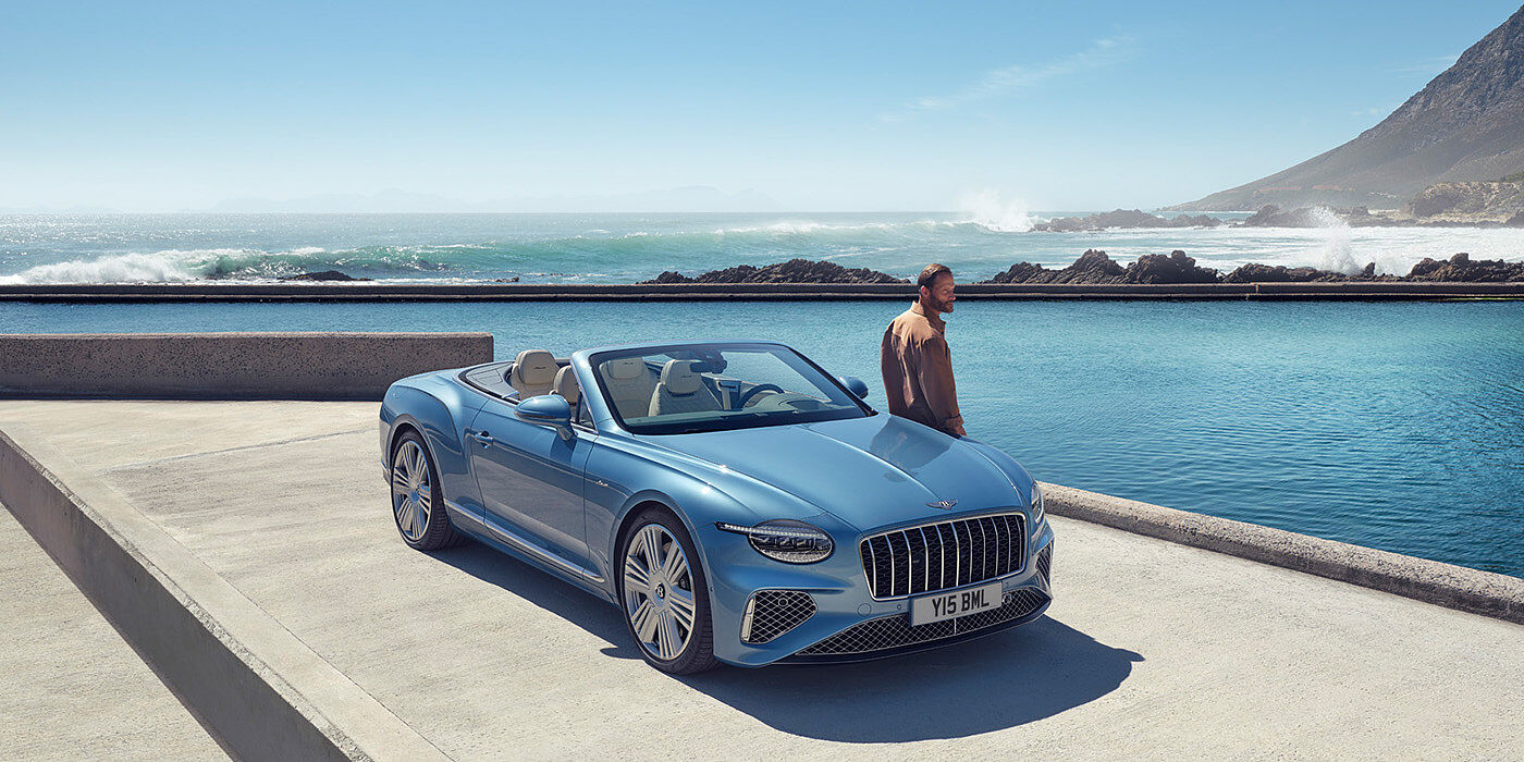 Bentley Kuala Lumpur New Bentley Continental GTC Azure convertible front view in Light Windsor blue paint with 22 inch ten spoke wheels parked by the sea in the sunshine