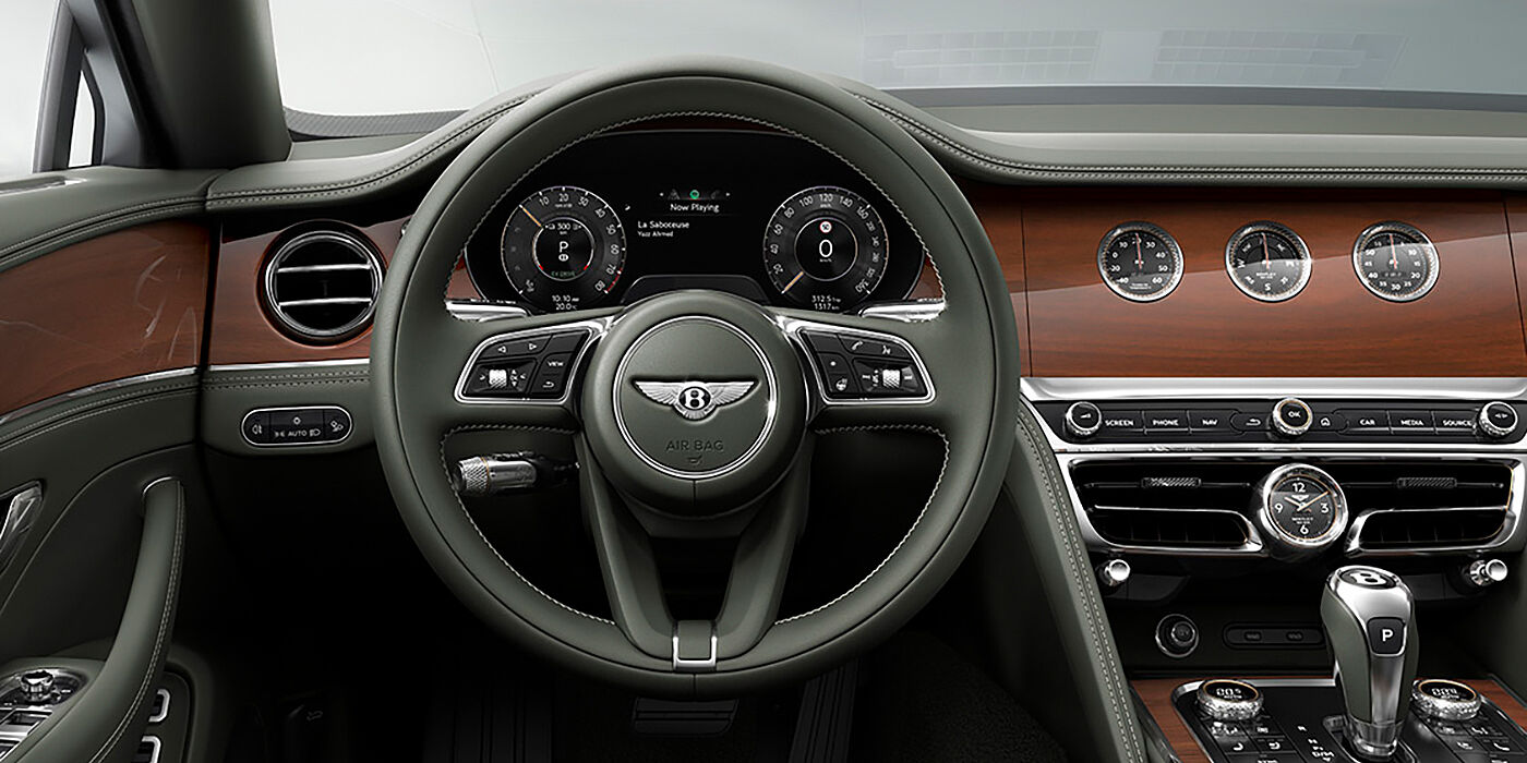 Bentley Kuala Lumpur New Bentley Flying Spur sedan front cabin in Cumbrian Green hide and Crown Cut walnut veneer showing steering wheel and Rotating Display with three clocks on face