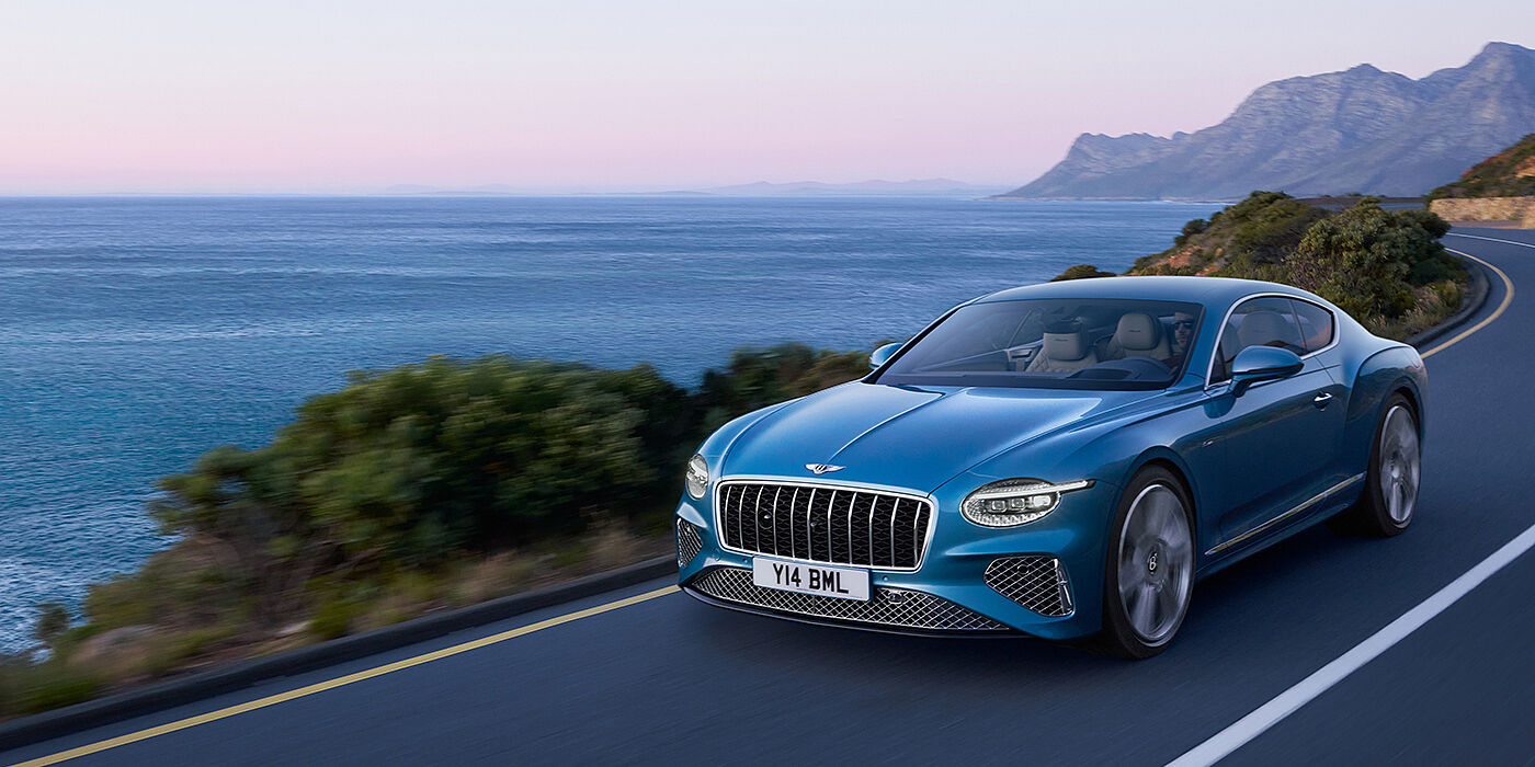 Bentley Kuala Lumpur New Bentley Continental GT Azure coupe in Light Windsor blue paint with 22 inch Azure wheels and chrome grill, driving dynamically by the sea