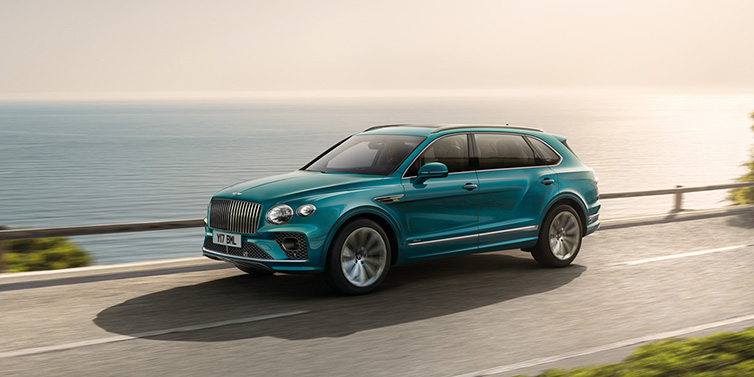 Bentley Kuala Lumpur Bentley Bentayga Extended Wheelbase Azure SUV in Topaz blue paint driving dynamically by the ocean