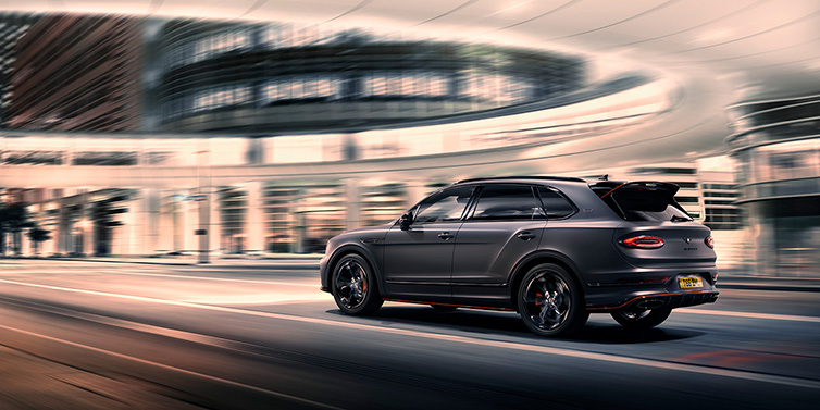 Bentley Kuala Lumpur Bentley Bentayga S Black Edition SUV rear three quarter in Anthracite Satin paint driving dynamically through a city at night