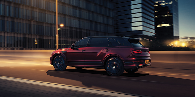 Bentley Kuala Lumpur Bentley Bentayga Extended Wheelbase Mulliner SUV in Cricket Ball red paint driving dynamically in city at night
